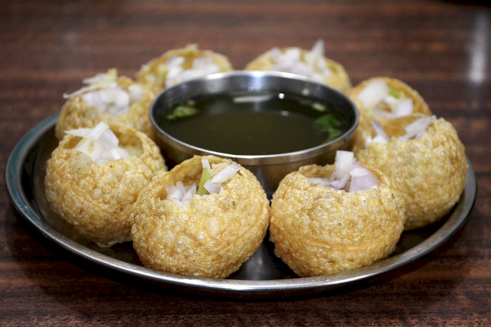 A burst of refreshing tang and spice, this iconic street food features crispy puris filled with tamarind water, creating a fun explosion of flavors in your mouth
